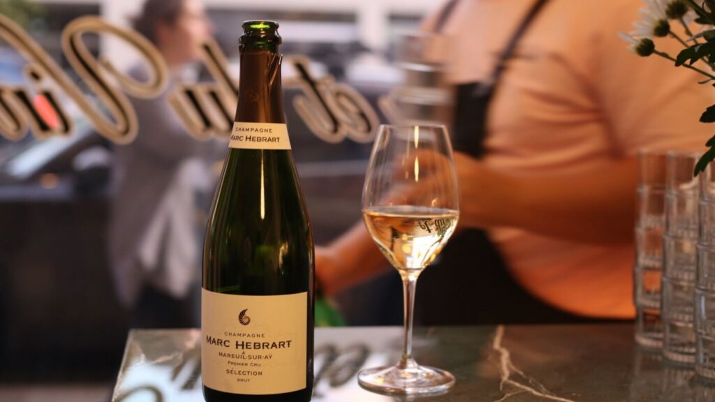 A bottle of grower Champagne beside a poured flute on the marble bar at Bar Septimus