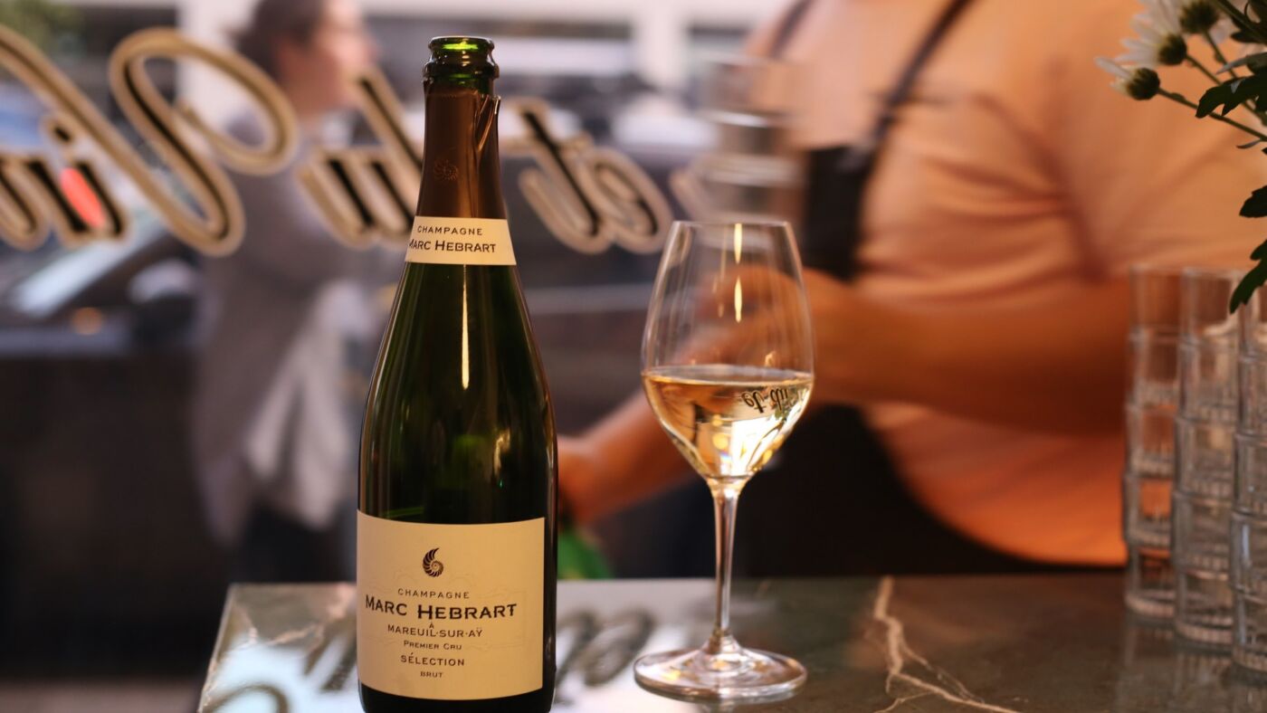 A bottle of grower Champagne beside a poured flute on the marble bar at Bar Septimus