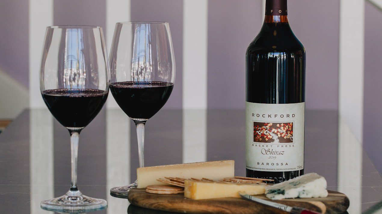 Two glasses of red wine beside a bottle of Barossa Shiraz and a board of hard and blue cheese at Bar Septimus