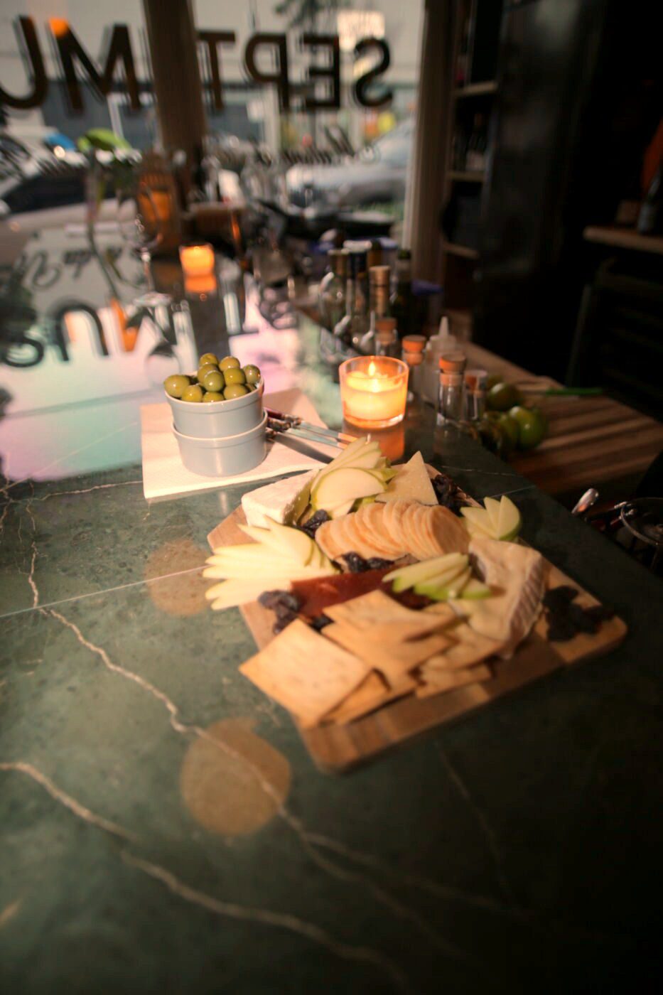 A cheese board on green marble with olives and a candle at Bar Septimus