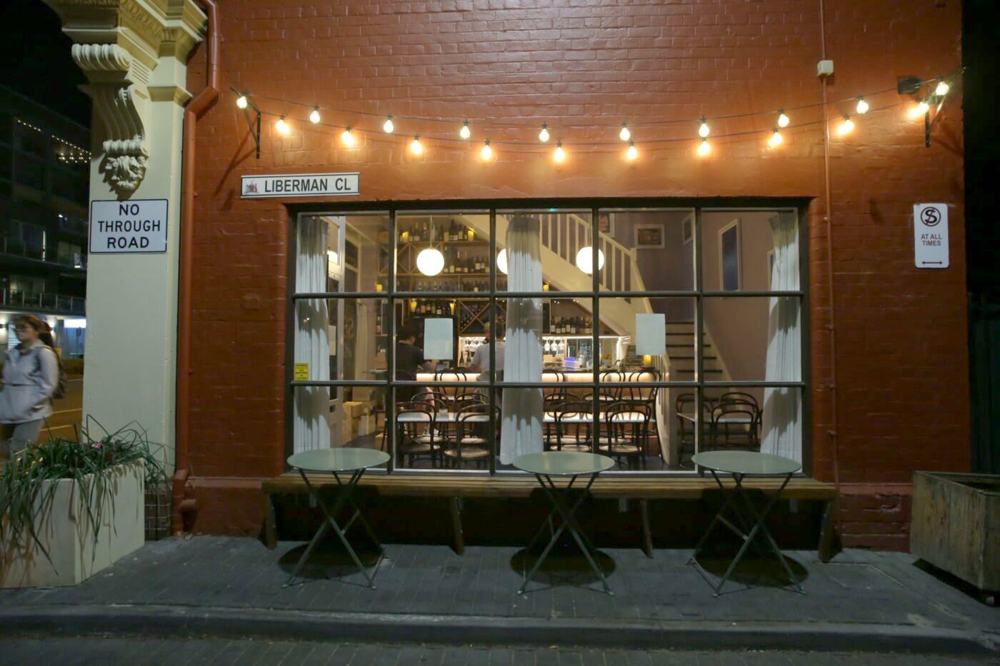 The Liberman Close window at Bar Septimus at night under festoon lights