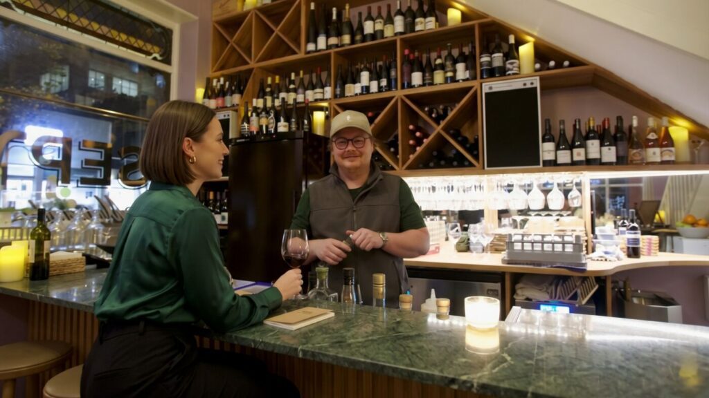 A guest with a glass of red at the marble bar, talking with Ed Rava